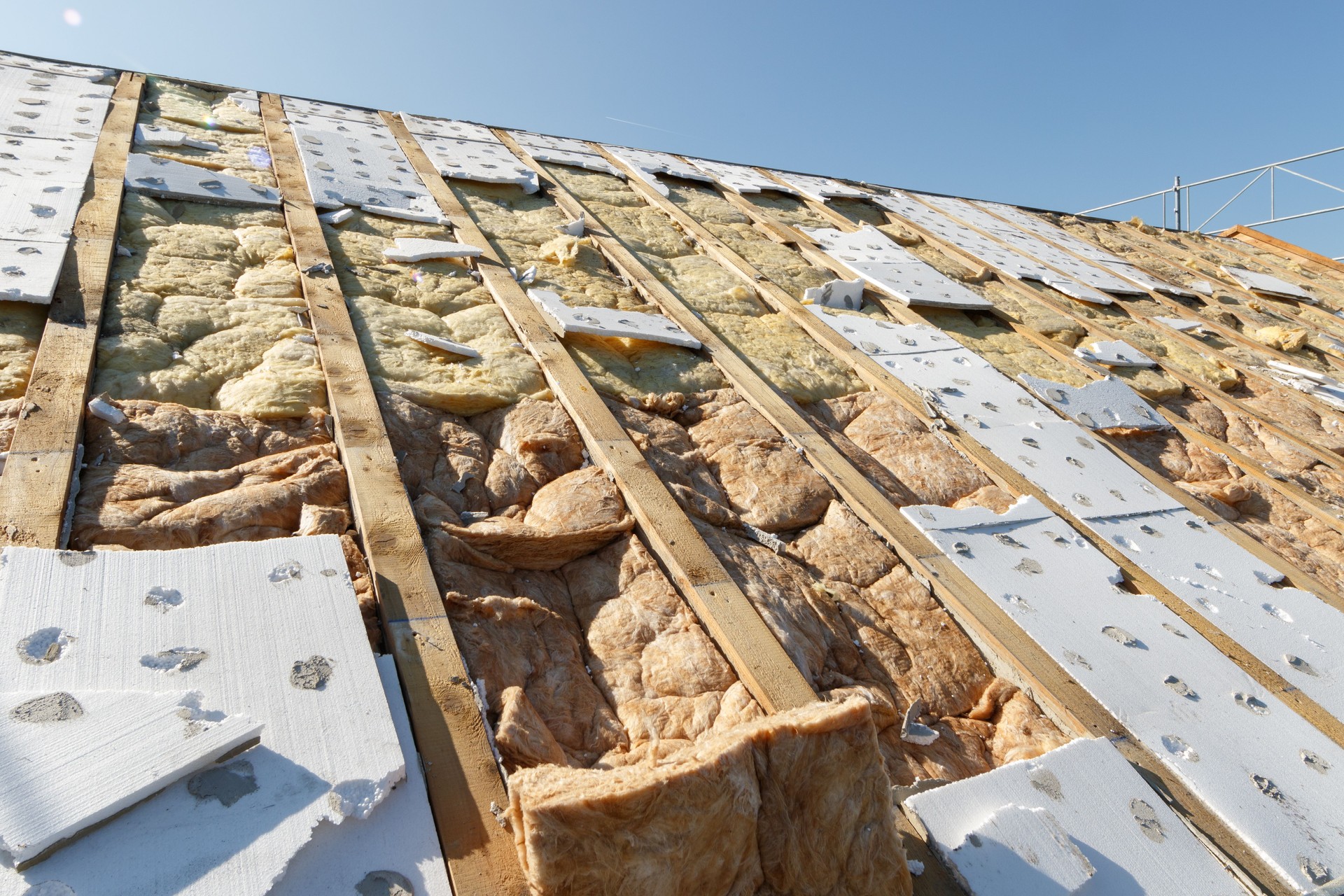 insulating wool fitted between the roof beams in front of the blue sky