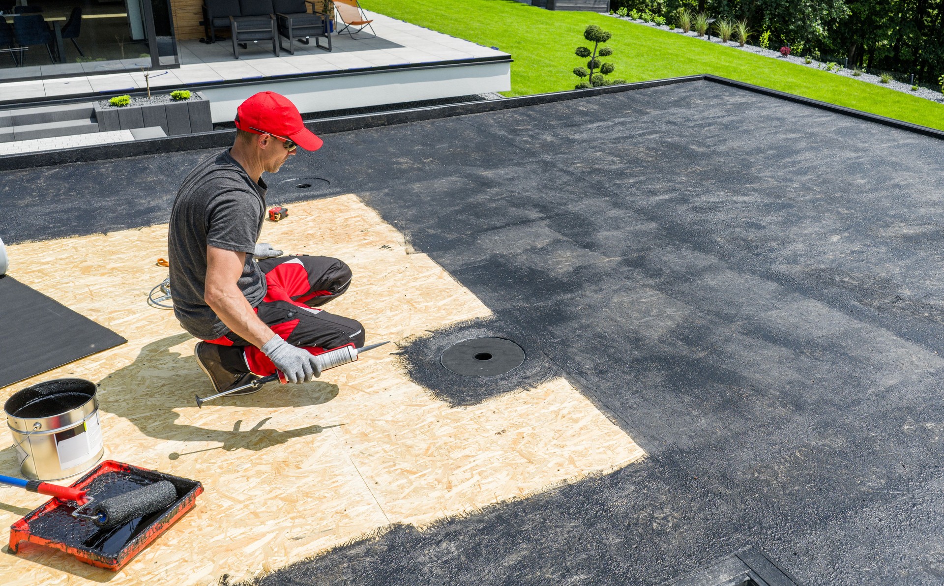 Worker Installing Roofing Material on a Flat Surface in Residential Area During Daytime