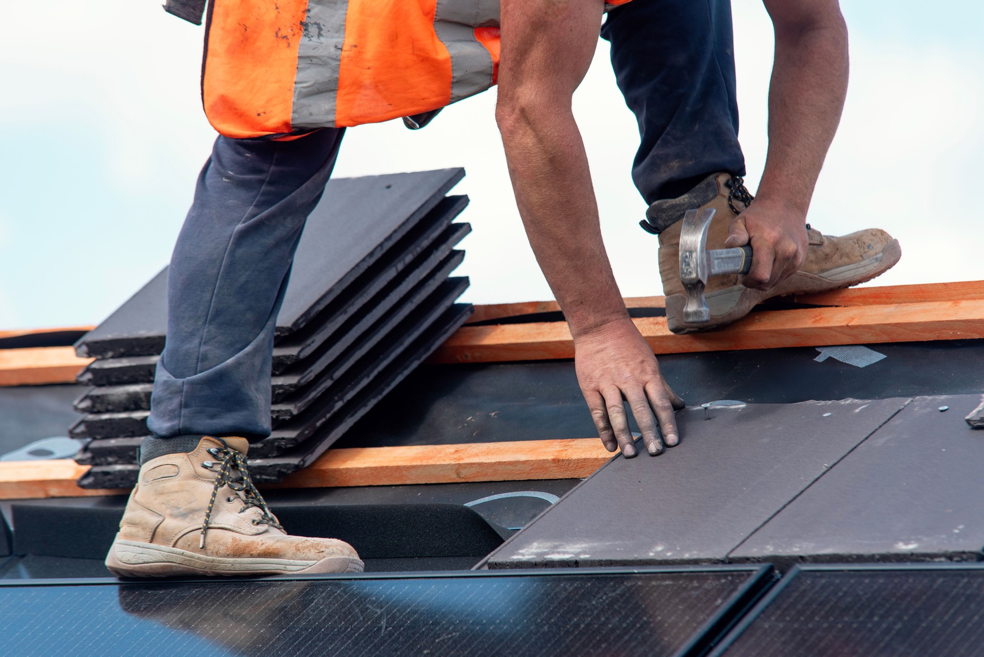 Construction worker roofers installing roofing tiles on residential building